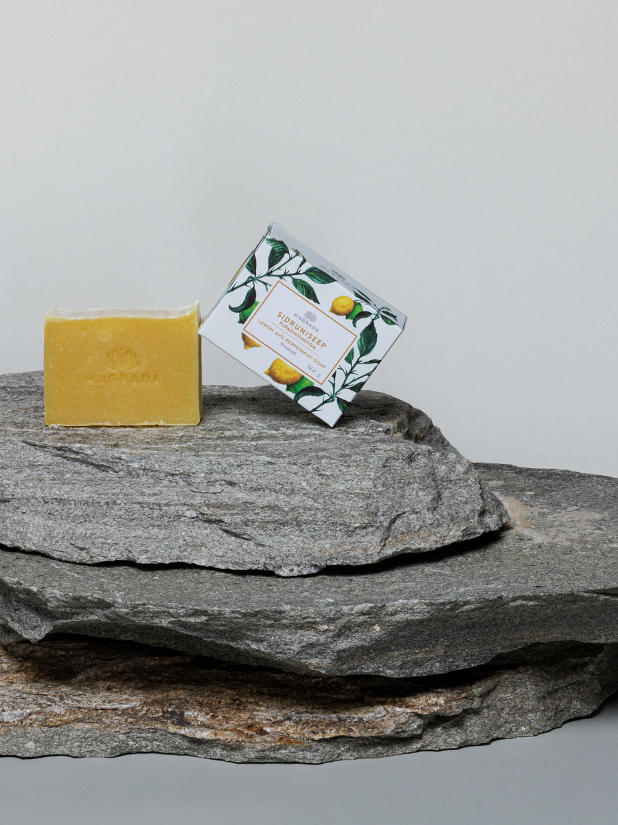 Natural handmade soap bar and decorative packaging by Magrada Organic Cosmetics displayed on stacked gray stones