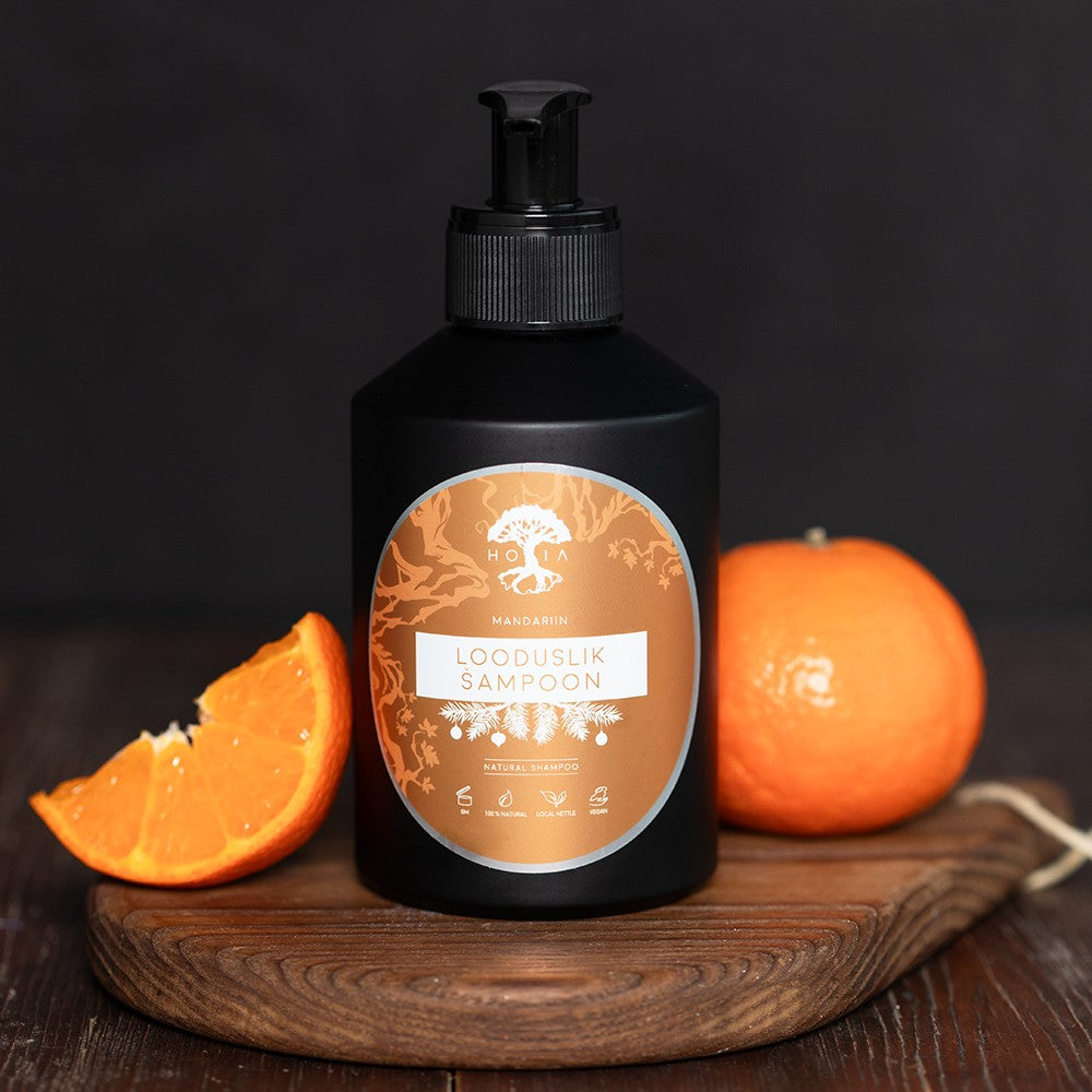 HOIA organic hair care mandarin shampoo bottle with fresh mandarin fruit on wooden board