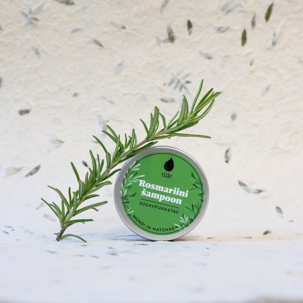 Tilk matcha shampoo bar in green tin with fresh rosemary branch on white textured background