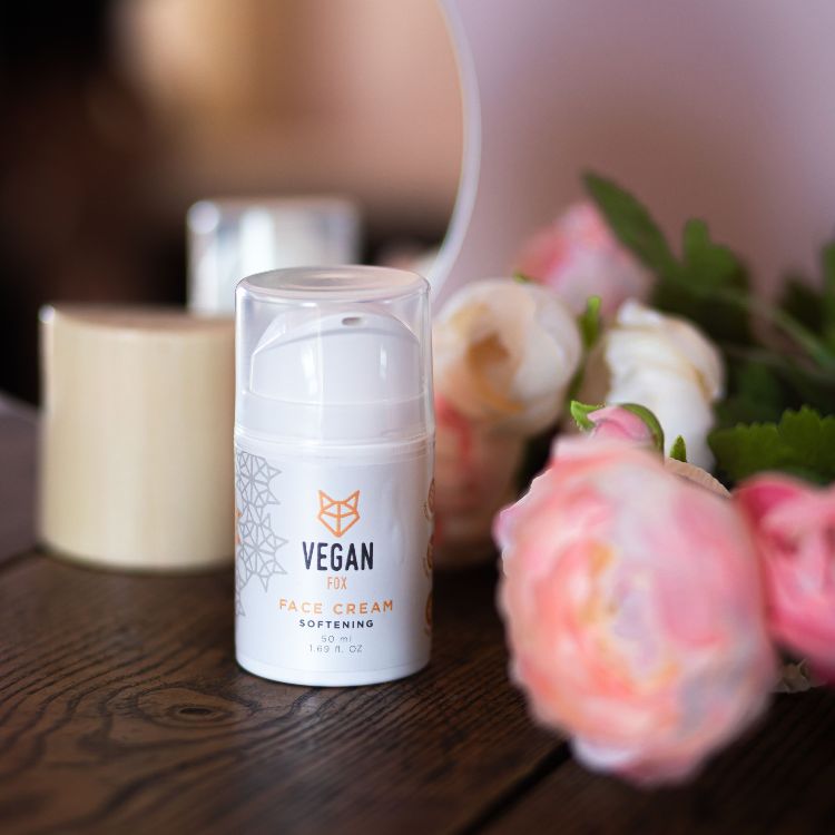 Vegan Fox vegan face cream hydrating in white pump bottle next to pink and white roses on wooden surface