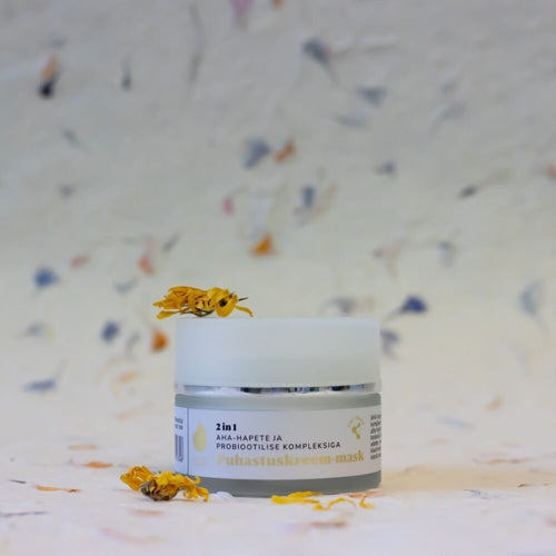 Tilk 2-in-1 cleansing cream mask in white jar with yellow flower petals on top and around